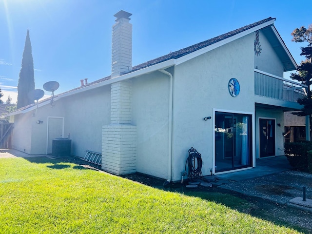 rear view of property with a patio, a yard, central AC unit, and a balcony