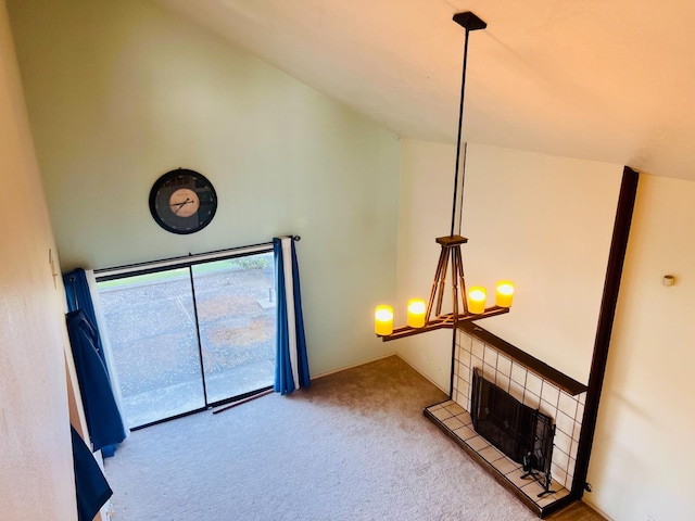 unfurnished living room featuring high vaulted ceiling, a notable chandelier, a tile fireplace, and light colored carpet