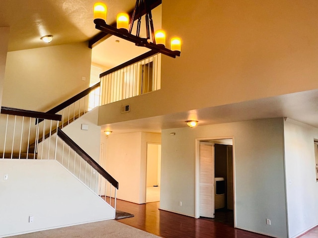 stairs with hardwood / wood-style floors, a chandelier, and a high ceiling