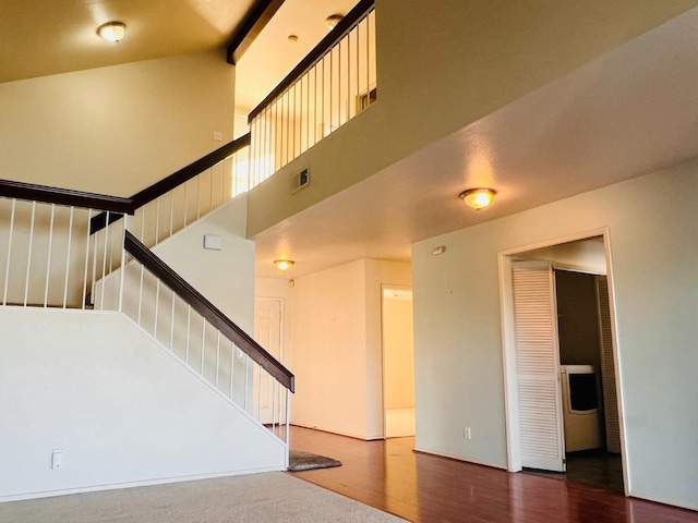 staircase featuring hardwood / wood-style flooring and a high ceiling