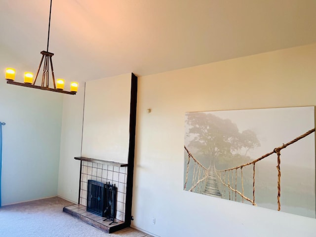 unfurnished living room with a notable chandelier, a tiled fireplace, and carpet