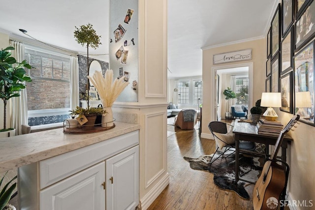 bar featuring light wood-type flooring, light stone counters, crown molding, and white cabinetry