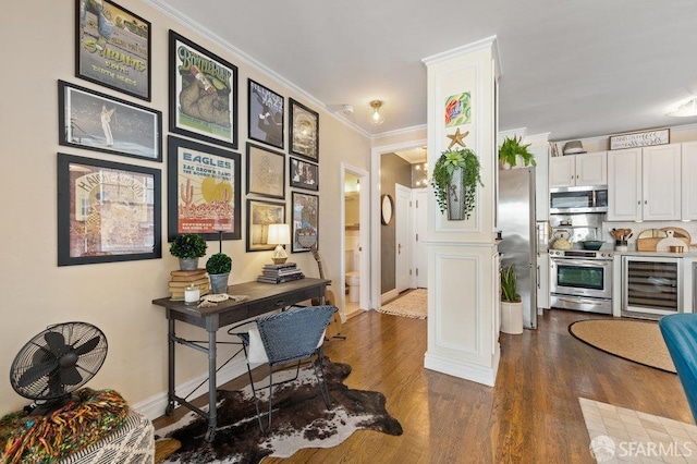 kitchen featuring appliances with stainless steel finishes, dark hardwood / wood-style floors, beverage cooler, crown molding, and white cabinets