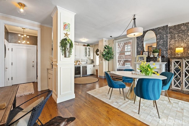 dining area featuring an inviting chandelier, ornamental molding, beverage cooler, and dark hardwood / wood-style floors