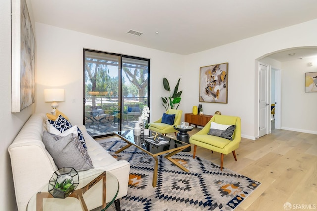 living area featuring visible vents, wood finished floors, arched walkways, and baseboards