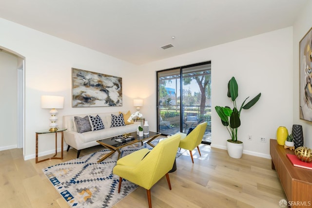 living room featuring baseboards, wood finished floors, visible vents, and arched walkways