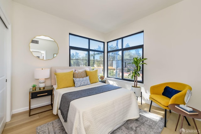 bedroom with wood finished floors, visible vents, and baseboards