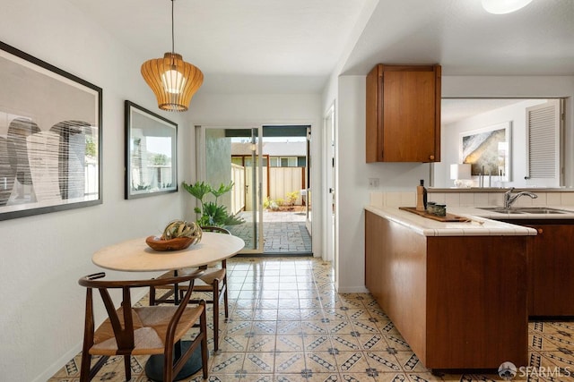 2691 Sean Ct, South San Francisco, CA 94080 - kitchen with tile countertops, brown cabinetry, a sink, decorative light fixtures, and baseboards