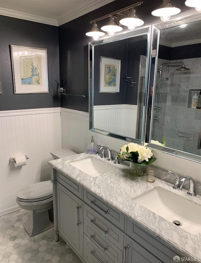 bathroom with vanity, crown molding, tiled shower, and toilet