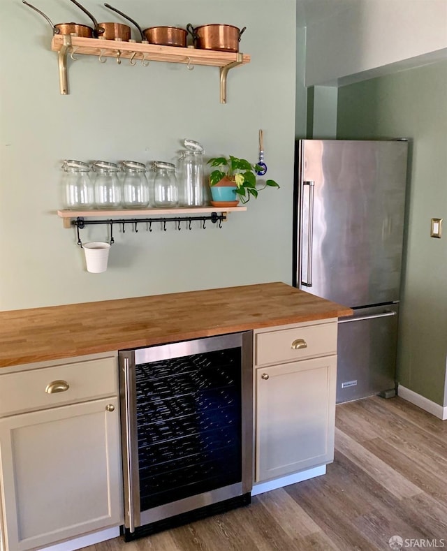 bar featuring light wood-type flooring, butcher block countertops, stainless steel fridge, white cabinets, and beverage cooler