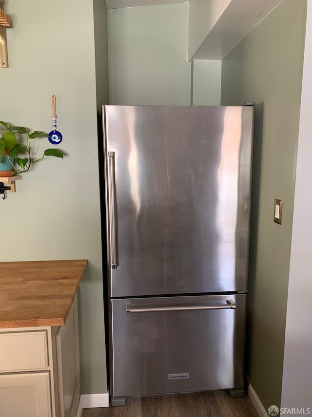 kitchen featuring wooden counters, stainless steel fridge, and dark hardwood / wood-style floors