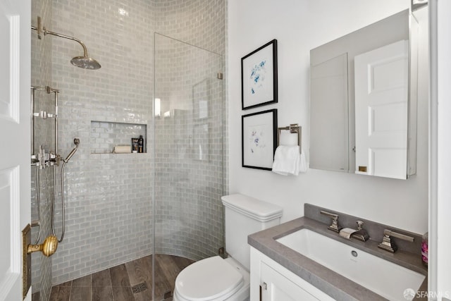 bathroom with vanity, toilet, and tiled shower