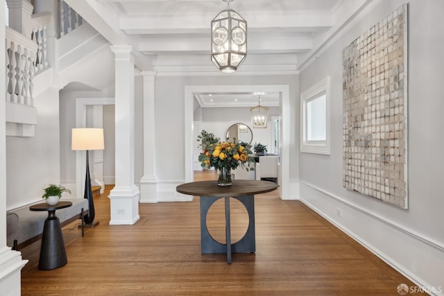 entrance foyer featuring crown molding, hardwood / wood-style flooring, a chandelier, and ornate columns