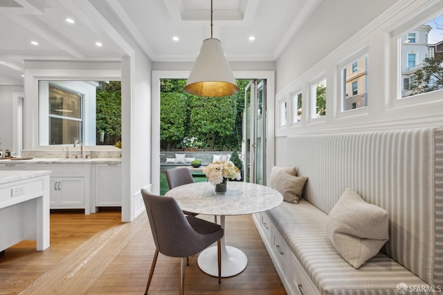 dining area featuring sink, ornamental molding, and light hardwood / wood-style floors