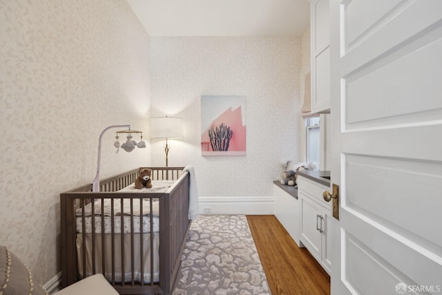 bedroom with a nursery area and hardwood / wood-style floors