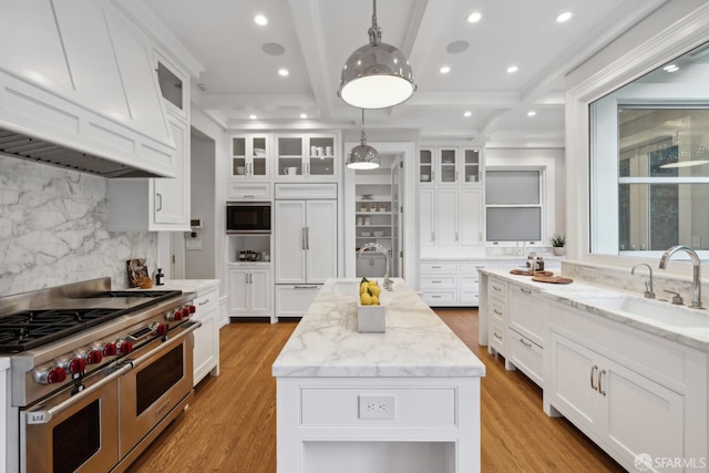 kitchen with sink, white cabinets, a center island, and built in appliances