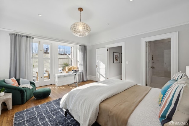 bedroom featuring french doors, hardwood / wood-style floors, and ensuite bath