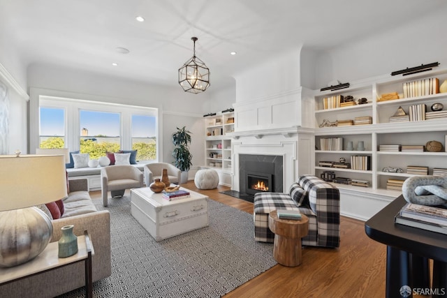 living room featuring a notable chandelier, a fireplace, and wood-type flooring