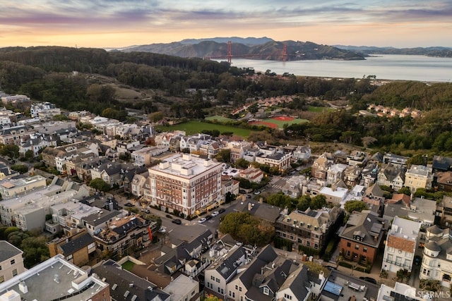 aerial view at dusk featuring a water and mountain view