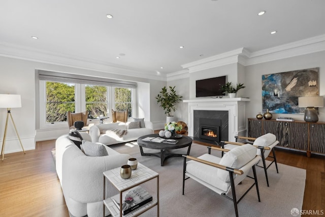 living room featuring a high end fireplace, crown molding, and light wood-type flooring