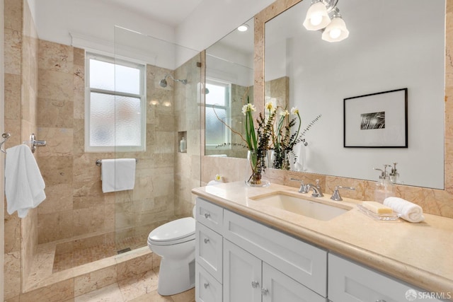 bathroom with a tile shower, vanity, and toilet