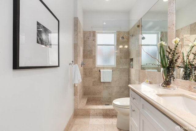 bathroom with toilet, plenty of natural light, vanity, and tiled shower