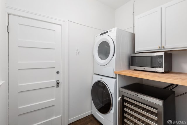 laundry room featuring cabinets, dark hardwood / wood-style floors, wine cooler, and stacked washer and clothes dryer