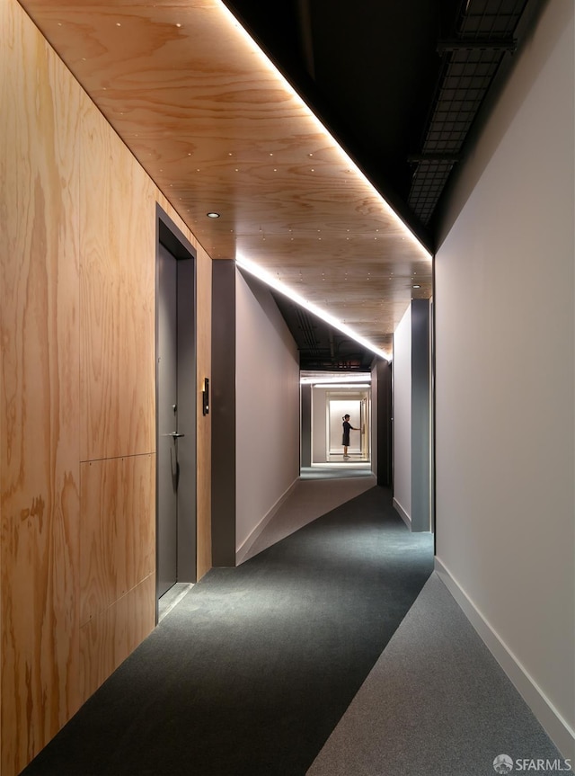 hallway with wooden ceiling and dark carpet