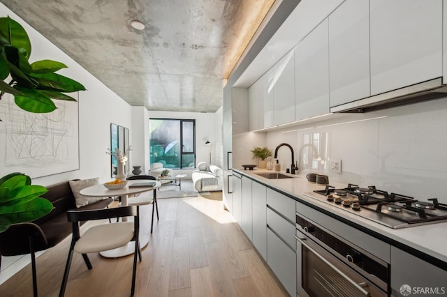 kitchen with white cabinetry, sink, stainless steel appliances, and light hardwood / wood-style floors