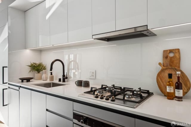 kitchen with wall oven, sink, exhaust hood, white cabinetry, and stainless steel gas stovetop