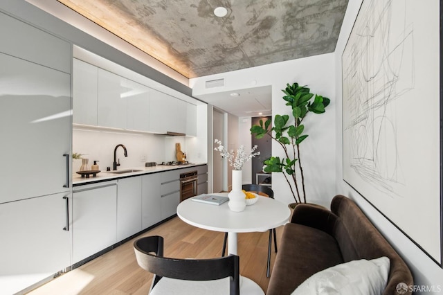 kitchen featuring stainless steel appliances, sink, white cabinets, and light hardwood / wood-style floors