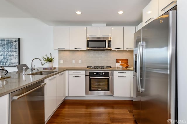 kitchen featuring a sink, white cabinetry, stainless steel appliances, a peninsula, and decorative backsplash