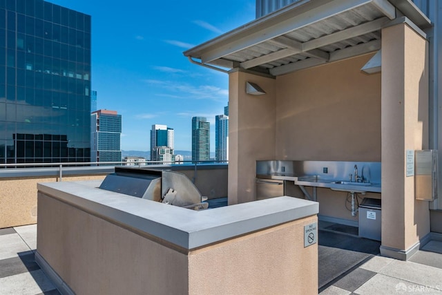 view of patio / terrace with a sink, a view of city, and exterior kitchen