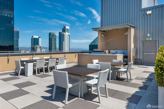 view of patio / terrace featuring a city view, exterior kitchen, and outdoor dining area