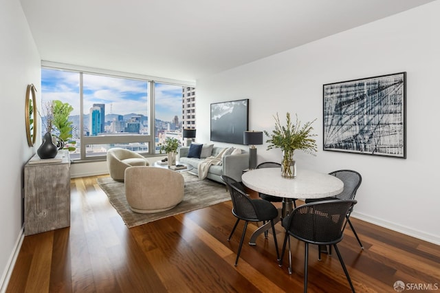 dining area with a view of city, wood finished floors, and baseboards