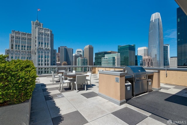 view of patio / terrace featuring a view of city, grilling area, and an outdoor kitchen