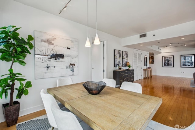 dining space featuring wood-type flooring and rail lighting