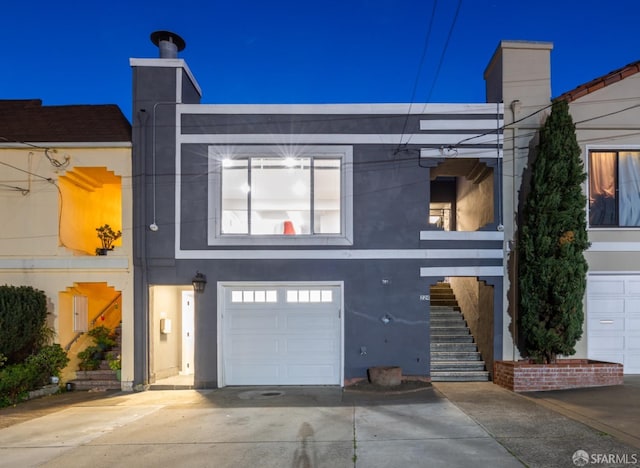 view of front facade featuring concrete driveway, stairway, an attached garage, and stucco siding