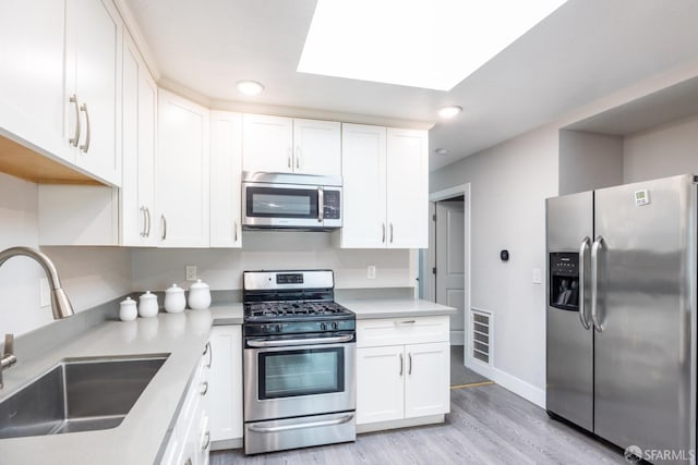 kitchen with visible vents, white cabinets, appliances with stainless steel finishes, light countertops, and a sink