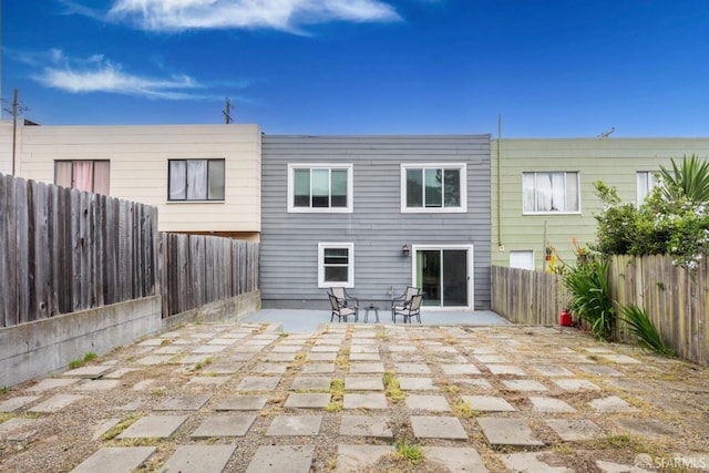 rear view of property featuring a patio area and a fenced backyard