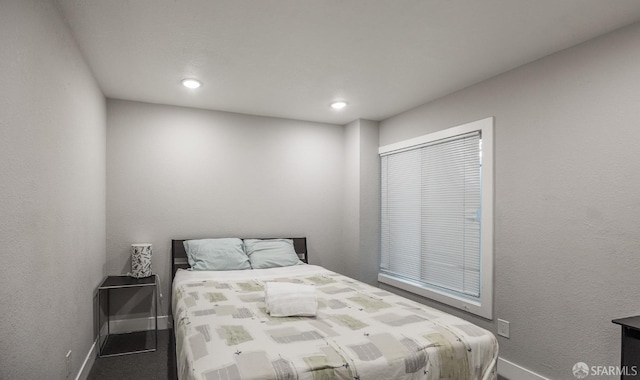 bedroom featuring a textured wall, recessed lighting, and baseboards