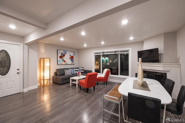 dining area featuring baseboards, a tile fireplace, dark wood-type flooring, beam ceiling, and recessed lighting