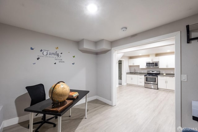 office space featuring light wood-style floors, a sink, and baseboards