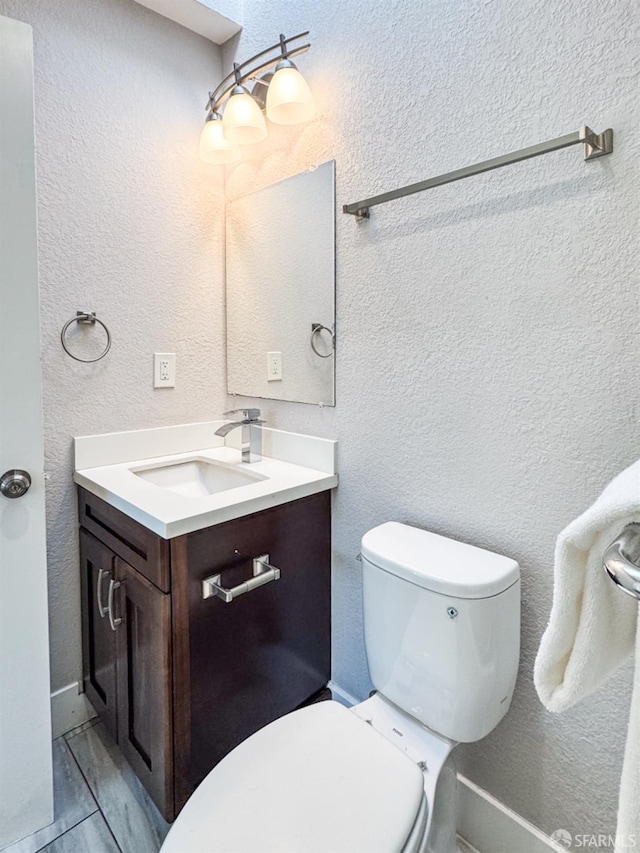 bathroom featuring a textured wall, vanity, and toilet