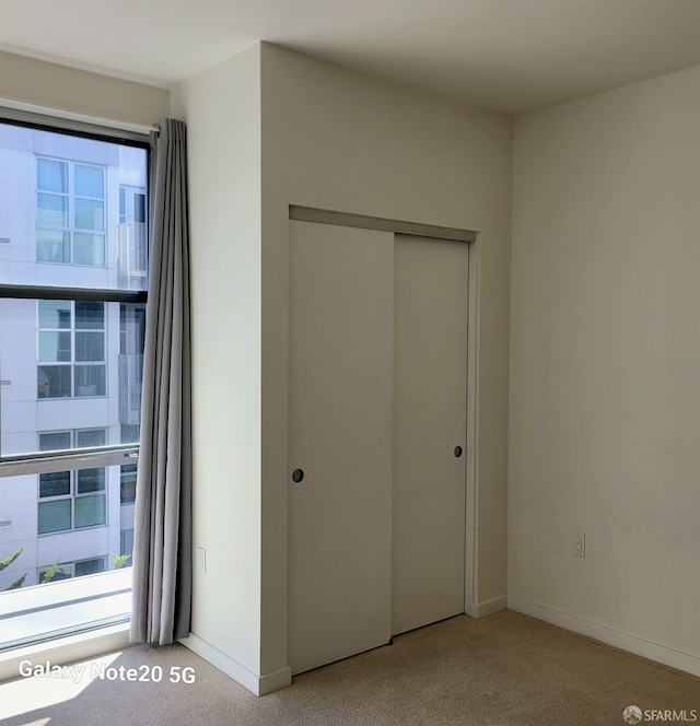 unfurnished bedroom featuring light carpet, a closet, and multiple windows