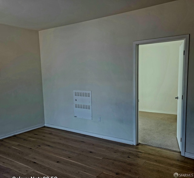 empty room with heating unit and dark hardwood / wood-style floors