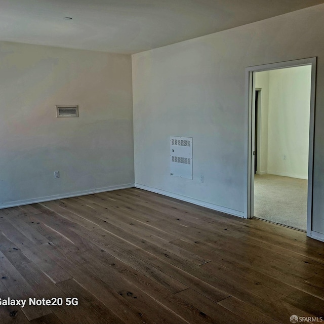 empty room with dark hardwood / wood-style floors and heating unit