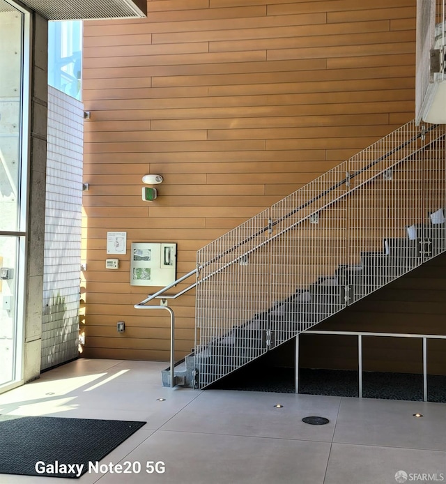 stairs with wood walls, a high ceiling, and a wealth of natural light