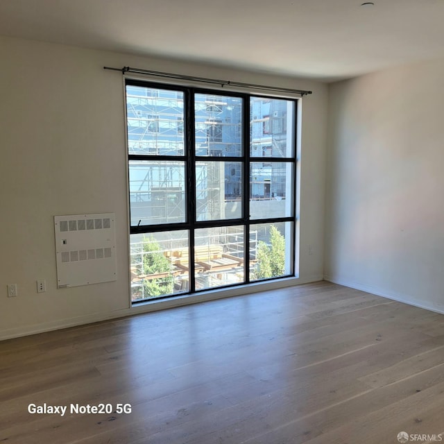 unfurnished room featuring wood-type flooring and heating unit