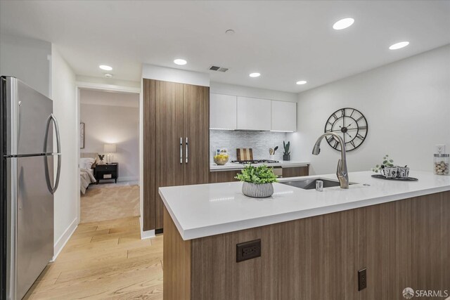 1080 Sutter St Unit 202, San Francisco, CA 94109 - kitchen with backsplash, sink, light wood-type flooring, appliances with stainless steel finishes, and white cabinetry